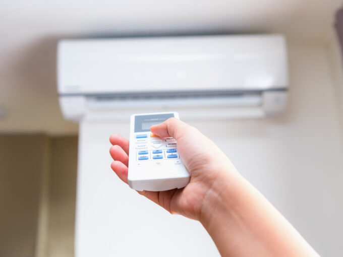 Close up view of hand operating air conditioner remote control.