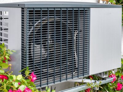 outdoor unit of a heat pump heating system surrounded by flowers