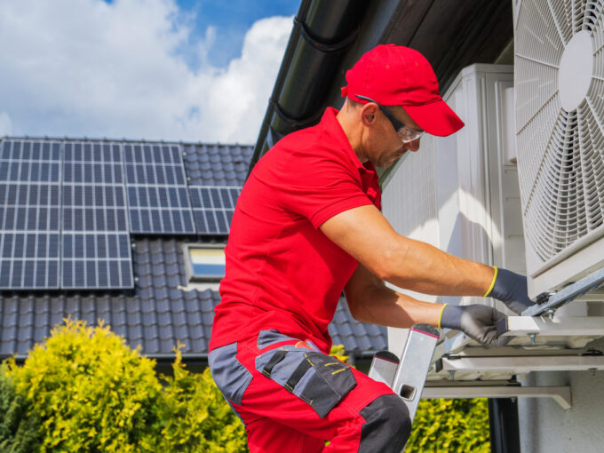 HVAC Worker Performing Heat Pump Maintenance. Device is Transferring Thermal Energy From the Outside Using the Refrigeration Cycle. Home Heating Technologies.